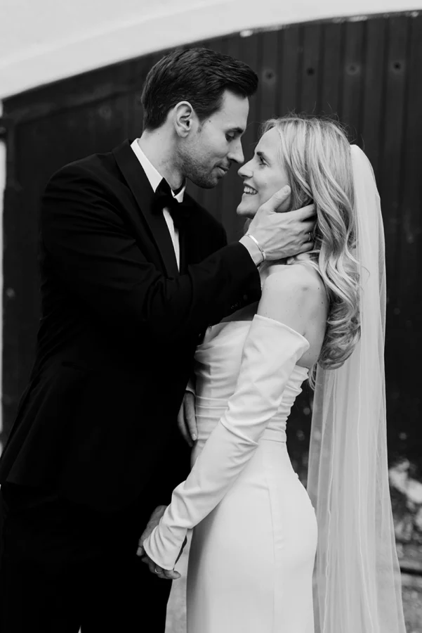Brautpaar in romantischer Umarmung, Bräutigam hält Braut zärtlich am Gesicht, Schwarzweiß-Hochzeitsfotografie Herford