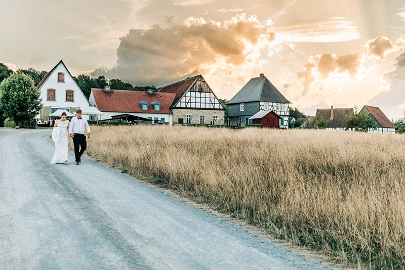 Brautpaar spaziert zur goldenen Stunde am Weißen Ross im Freilichtmuseum Detmold