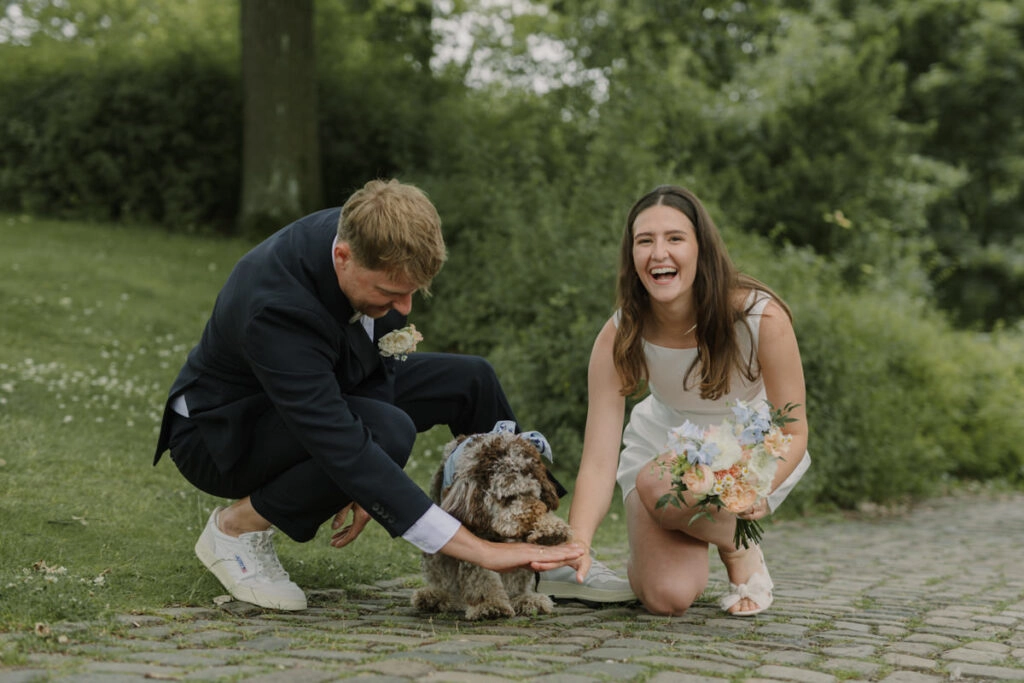 Brautpaar lacht mit seinem Hund nach der standesamtlichen Trauung auf der Sparrenburg