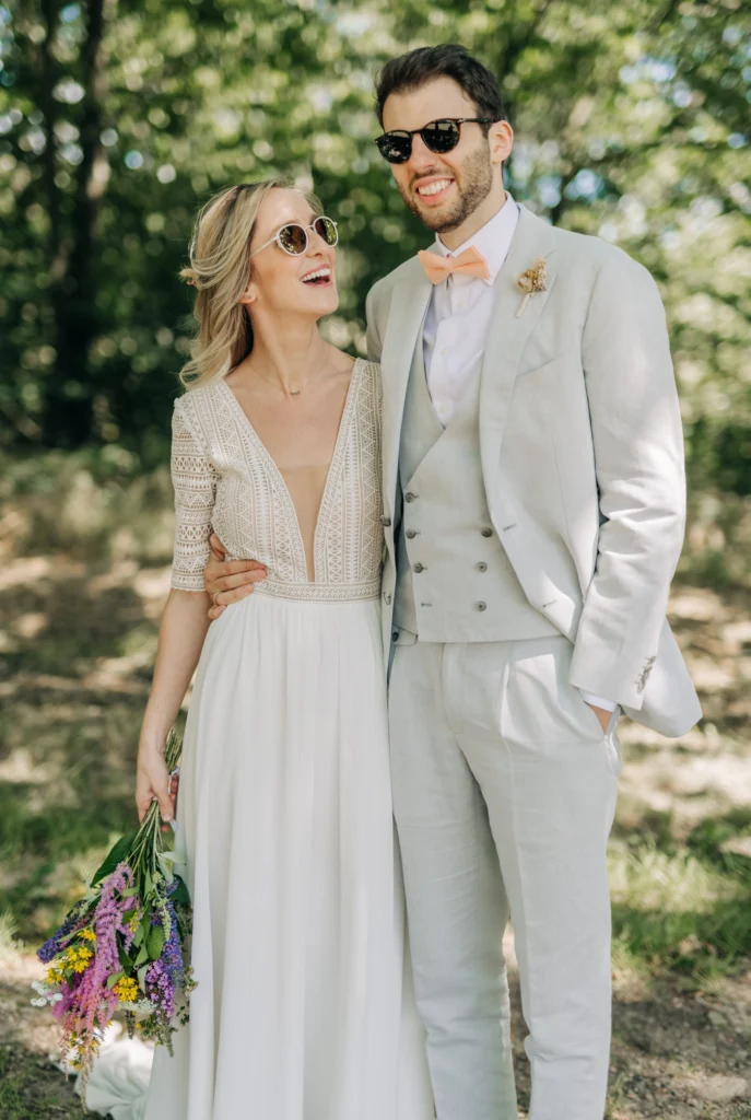 Brautpaar mit Sonnenbrille und Wildblumenstrauß bei der Hochzeit an der Sparrenburg