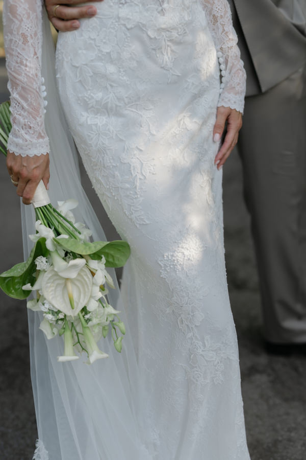 Detail von Samiras Spitzenkleid und ihrem weiß-grünen Brautstrauß