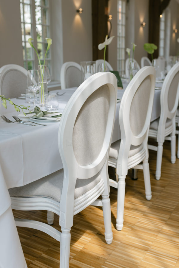 Lange Hochzeitstafel mit weißen Stühlen in der Orangerie des Wasserschlosses Holtfeld
