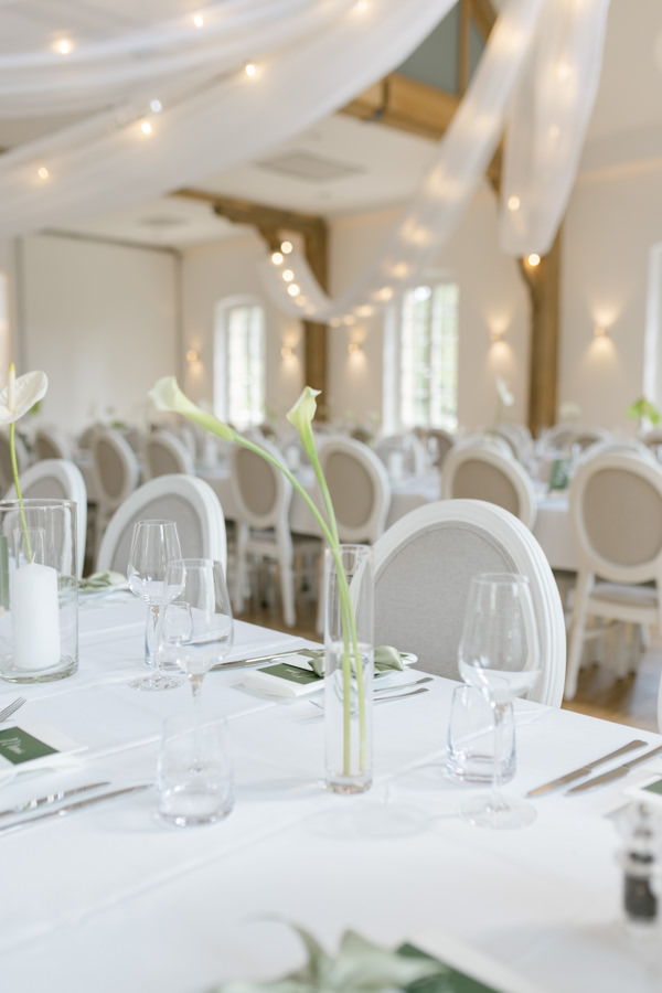 Helle Tischdekoration mit weißen Blumen und Kerzen in der Orangerie